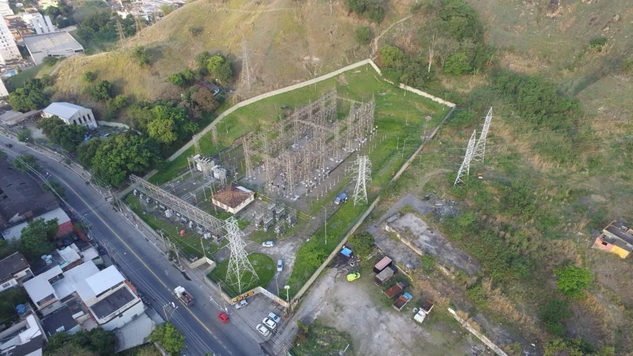 Vista aérea de subestação em encosta, ao lado de avenida e área urbana